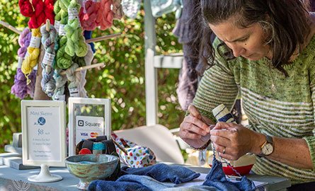 A woman crafting outside at a booth